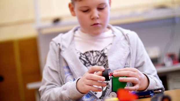 the boy of 11 years, plays in the designer from cubes, plates, circuits, wires. a small inventor creates robots, machines from different parts of the designer. High quality photo