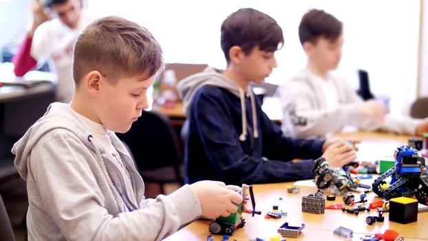 boys of 12 years, play in the designer from cubes, plates, circuits, wires. small inventors create robots, machines from different parts of the designer. High quality photo