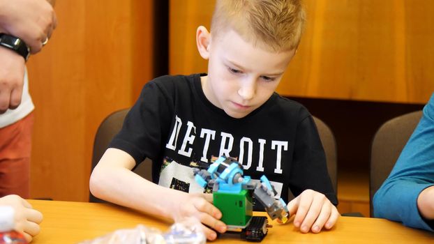 the boy of 9 years, plays in the designer from cubes, plates, circuits, wires. a small inventor creates robots, machines from different parts of the designer. High quality photo