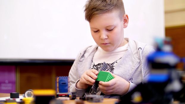 the boy of 11 years, plays in the designer from cubes, plates, circuits, wires. a small inventor creates robots, machines from different parts of the designer. High quality photo