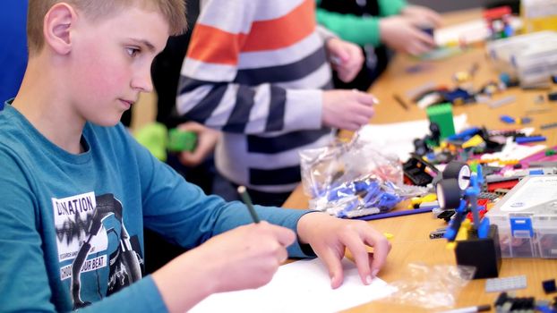 the boy of 12 years, draws a drawing, a project of a robot model, a machine, plays in the designer from cubes, plates, circuits, wires. he is fond of robotics, programming, modeling,. High quality photo