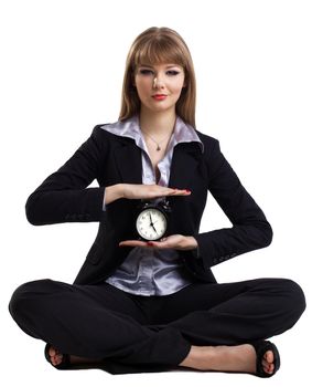 Yong business woman sit in yoga pose with clock - isolated