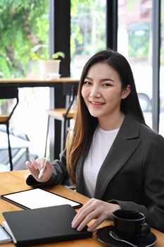 Attractive businesswoman sitting in office and smiling to camera.