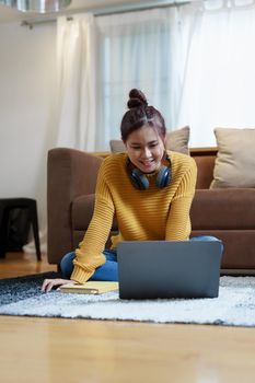 Portrait of a young Asian woman using a computer on the sofa.