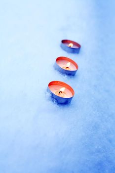 Few lighting candles on snow surface with free space