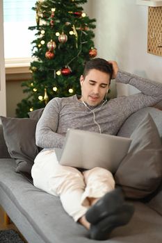 Casual man sitting on comfortable sofa and using laptop computer.