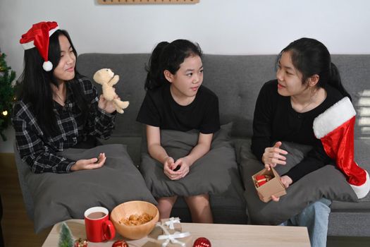 Three asian children sitting on sofa and celebrating Christmas at home.