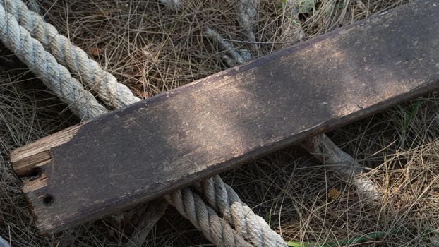 Wooden board and thick rope rope on dry grass. High quality photo