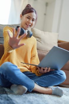 Portrait of a young Asian woman using a computer on the sofa.