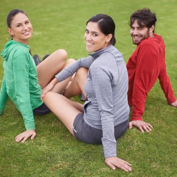 Looking great and we know it. Portrait of young people in exercise clothing sitting on a grassy sports field