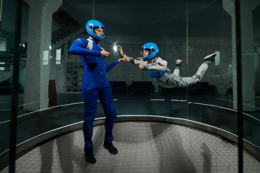 A man teaches a woman how to fly in a wind tunnel. Free fall simulator