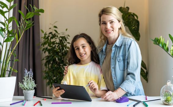 Back to school. Happy child and adult are sitting at desk. Girl doing homework or online education.