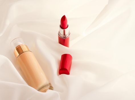 Cosmetic branding, glamour and skincare concept - Beige tonal cream bottle make-up fluid foundation base and red lipstick on silk background, cosmetics products as luxury beauty brand holiday design