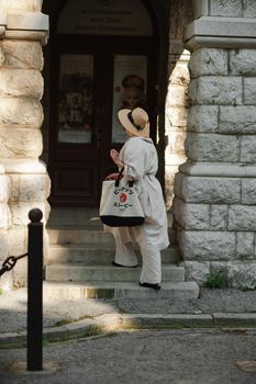 A woman in a hat in a white outfit with a bag walks around the Livadia Palace.
