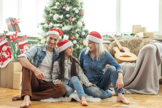 Merry Christmas and Happy New Year. Happy family on the living room floor one after another and laughing near beautiful Christmas tree at home. Happy family and kid.