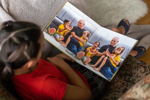 A Little Caucasian girl holding a photobook with her photographs in her hands.