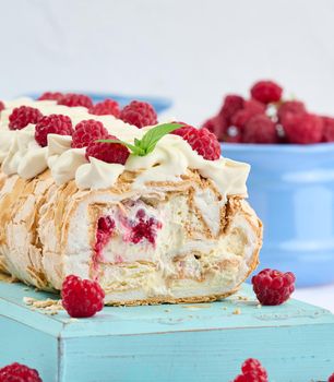 Baked meringue roll with cream and fresh red raspberry, white background	