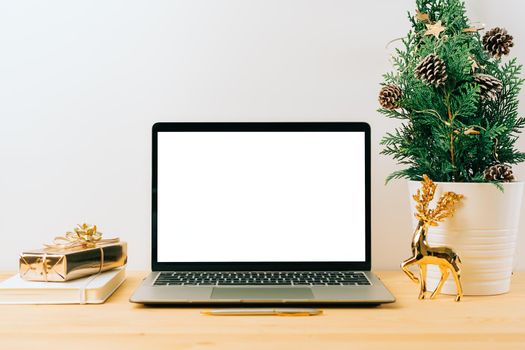 Laptop with mockup blank screen on wooden table with Christmas gift, fir tree on white background. Computer with Mock up and copy space for text.