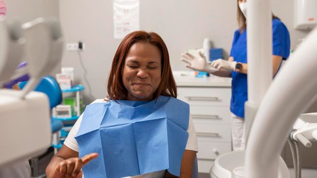 A black woman patient makes a funny face when tasting the mouthwash liquid at the dental clinic