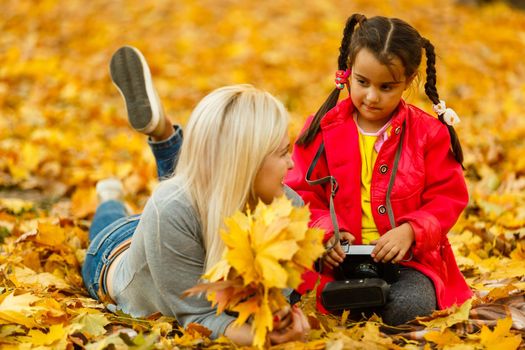 woman with daughter Outdoor having fun in autumn park.