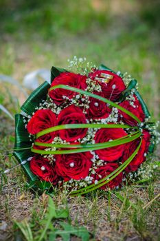 Bridal wedding bouquet of flowers. Wedding bouquet of red roses lying on a grass.