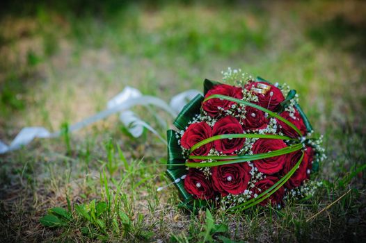 Bridal wedding bouquet of flowers. Wedding bouquet of red roses lying on a grass.