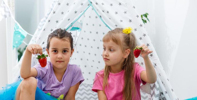 two little girls eating strawberries.