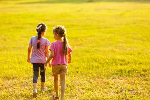 two little girls walking in the field