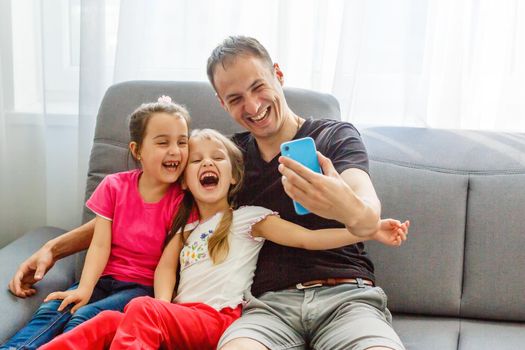 Young father with his cute little daughters taking selfie.