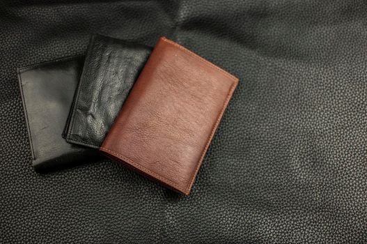 Stylish leather wallets on black leather background