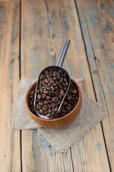 Roasted coffee beans in a wooden bowl. Close up. Copy space. 