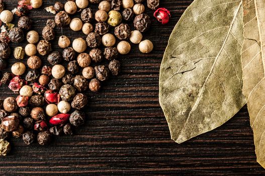 Spice. Bay leaves and pepper mix on a dark wooden table. 