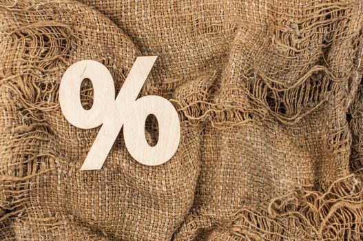 Wooden sign percent on background of burlap hessian sacking