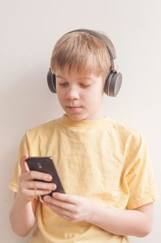 Happy teen boy is listening music with headphones