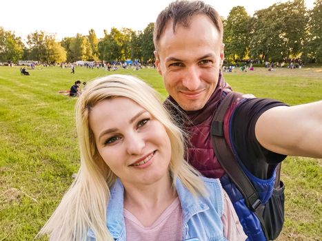 Happy young couple hugging. Man and woman making selfies isolated on green background.