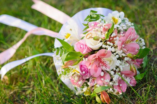 Bridal wedding bouquet of flowers. Wedding bouquet of yellow and white roses lying on a grass