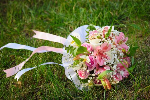 Bridal wedding bouquet of flowers. Wedding bouquet of yellow and white roses lying on a grass