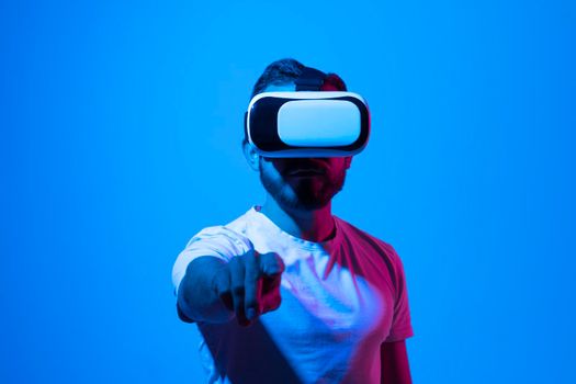 Bearded man in VR glasses, playing video games with virtual reality headset, trying to touch something with hand. VR, future, gadgets, technology, studying, video game concept, metaverse