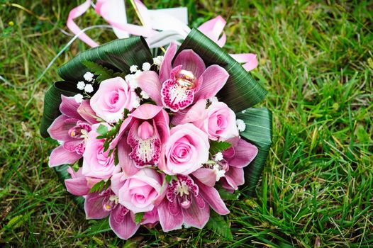 Bridal wedding bouquet of flowers. Wedding bouquet of pink roses lying on a grass.