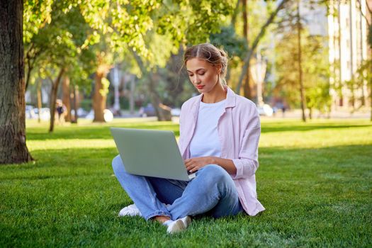 Businesswoman sitting grass summer park using laptop Business persone working remote. Outdoors Successful european caucasian woman freelancer make video call teacher study work online lessons