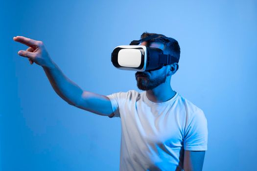 Young bearded man wearing virtual reality glasses and playing video games