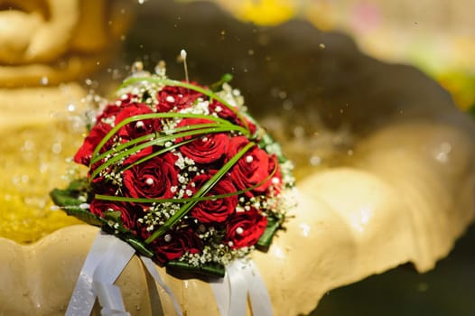 The Wedding Bouquet Of The Bride Of Red Roses Lies In An Old Fountain Under Splashes And Drops Of Water.. bridal bouquet of flowers in fountain water drops