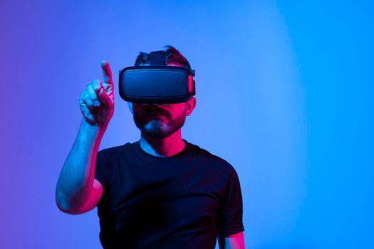 Future Technology and Business Concept. The man in a black t-shirt with glasses of virtual reality touching something in a virtual space in a dark room