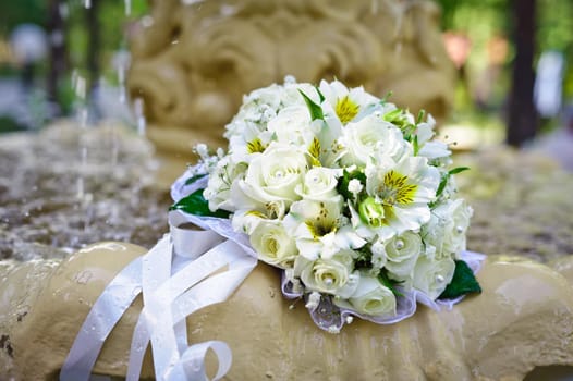 The Wedding Bouquet Of The Bride Of Red Roses Lies In An Old Fountain Under Splashes And Drops Of Water.. bridal bouquet of flowers in fountain water drops