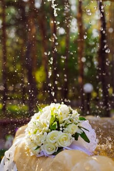 The Wedding Bouquet Of The Bride Of Red Roses Lies In An Old Fountain Under Splashes And Drops Of Water.. bridal bouquet of flowers in fountain water drops