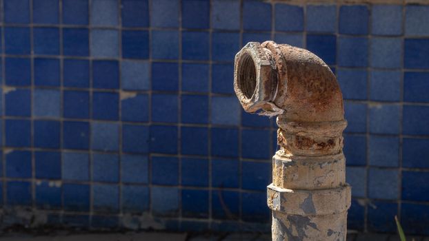 Metal rusty pipe on the background of blue facing tiles. High quality photo