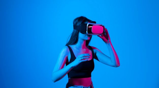 Amazed brunette woman in black top using virtual reality glasses. Amazed famale in vr headset. Virtual gadgets for entertainment, work, free time and study