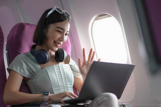 Asian young woman using laptop sitting near windows at first class on airplane during flight,Traveling and Business concept.