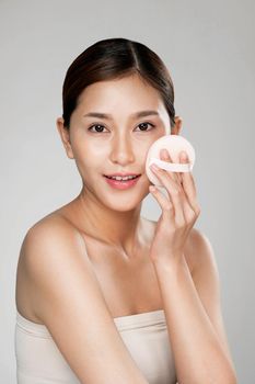 Ardent woman applying her cheek with dry powder and looking at camera. Portrait of younger with perfect makeup and healthy skin concept.