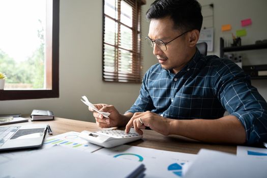 Young asian man calculating expenses household about finance and frustrated on desk at home, male checking bill having stress and worried, debt and tax, expression and emotion, business concept